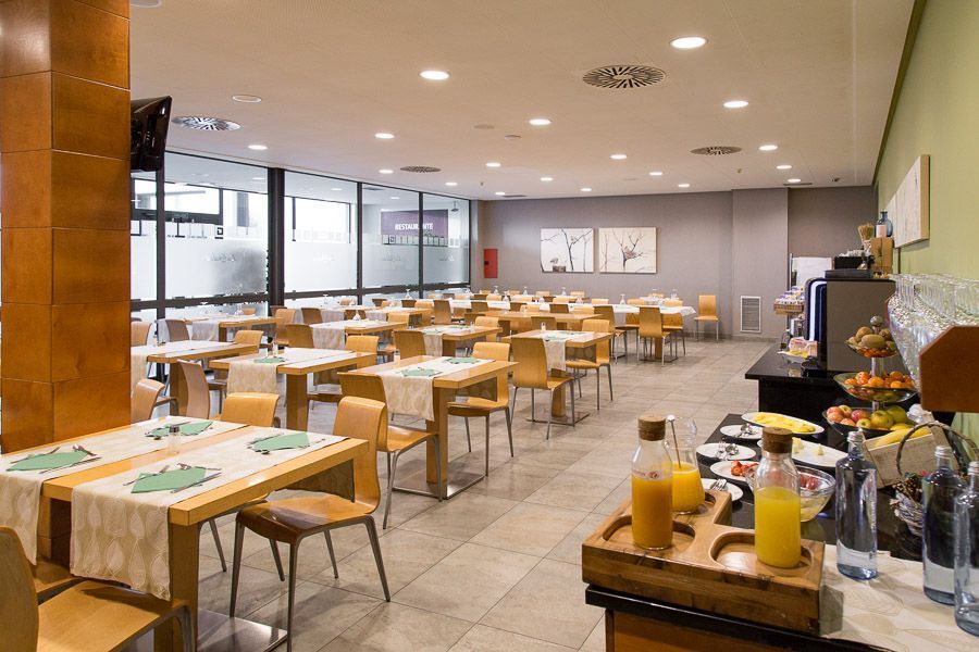 Comedor del menú del día con mesas montadas, cristalera y cuadros en las paredes.